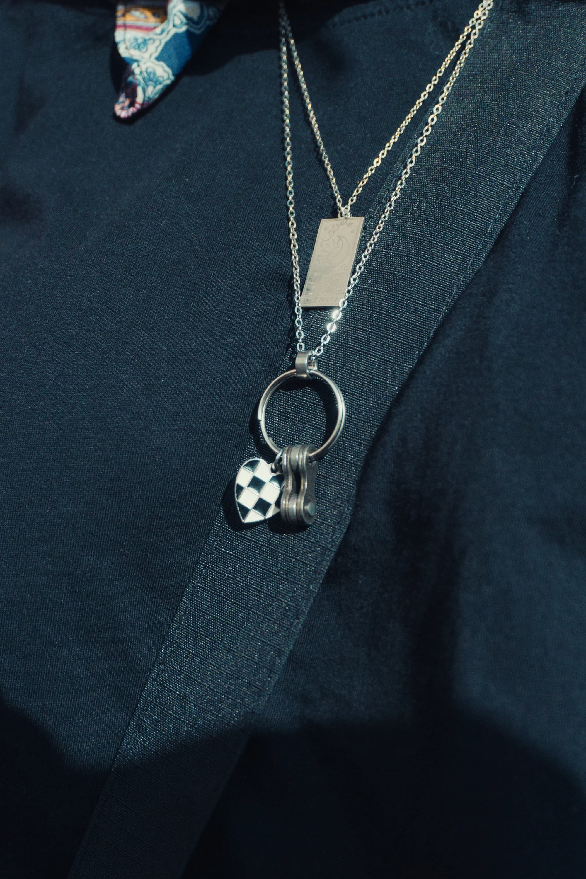 Silver pendant necklace worn over a dark top